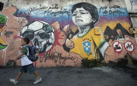 A boy walks in front of graffiti painted against infrastructure work for the 2014 World Cup at the Metro Mangueira slum in Rio de Janeiro