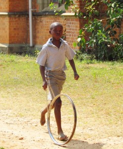 boy playing with old bicycle steel rim and stick